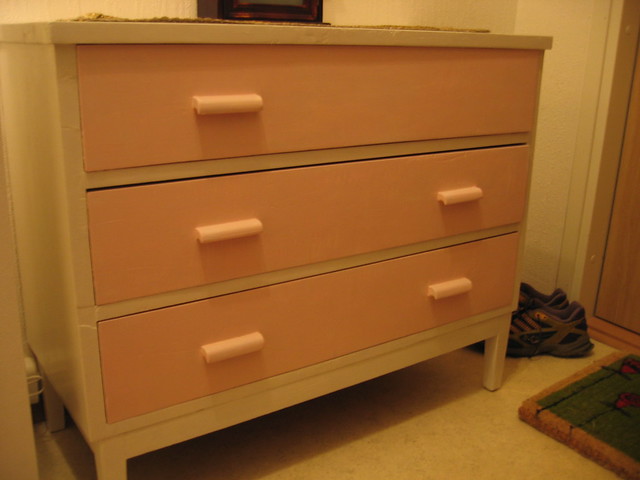 The pink chest of drawers with the missing knob in one spot