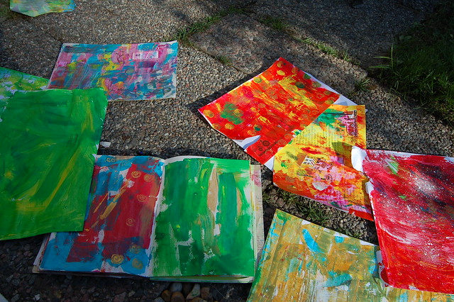 Painted background paper spread out on the ground outdoors as I experiment and smear, stain and spill acrylic paint onto paper (Copyright H. Andersson)